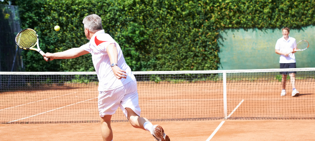 A father and son playing tennis on a clay court